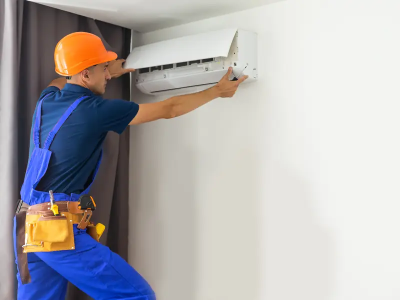 Climatisation et canicule : bien la régler, l'aider à tenir, réagir en cas de panne 2 Installateur intervenant sur une unité murale de climatisation