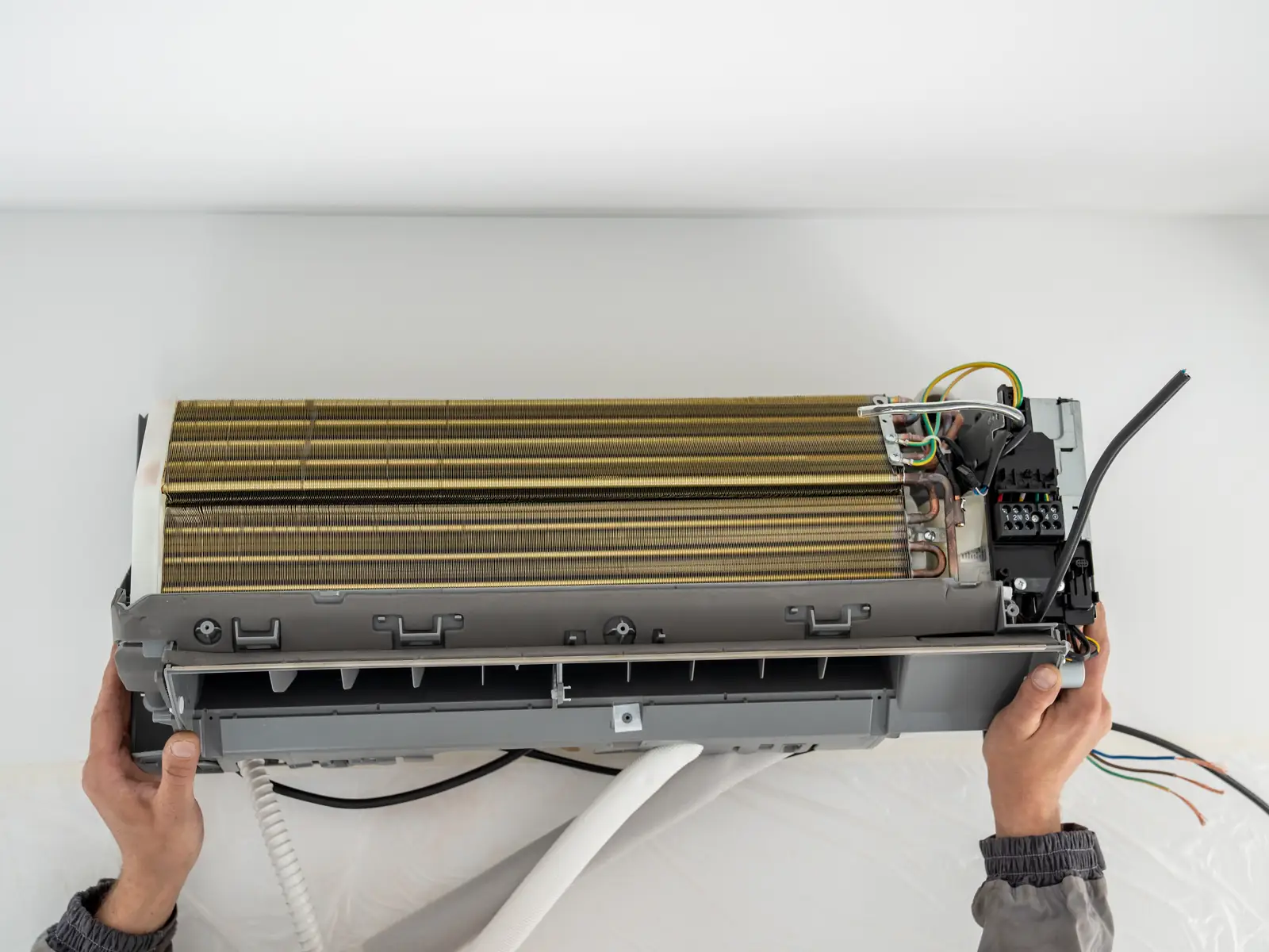 Installateur raccordant une unité intérieure de climatisation au mur