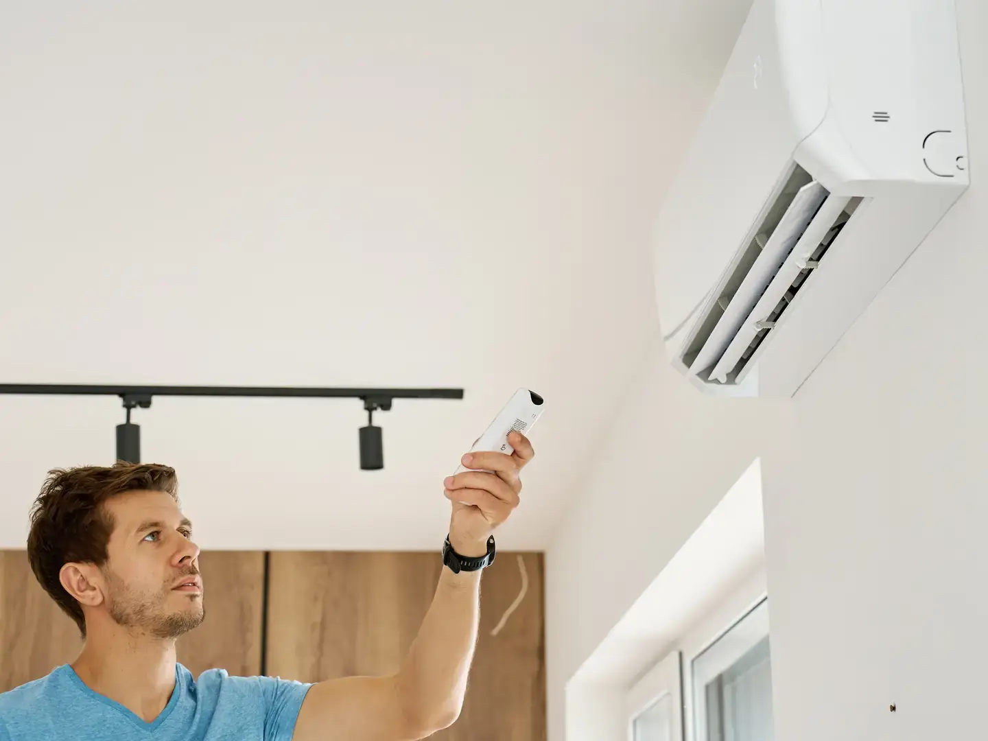 Personne mettant en marche une climatisation murale avec la télécommande