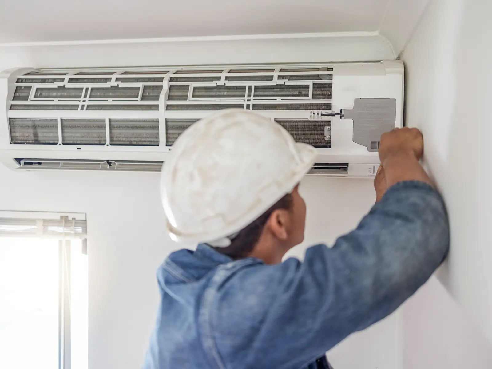 Technicien diagnostiquant une panne sur une unité murale de climatisation