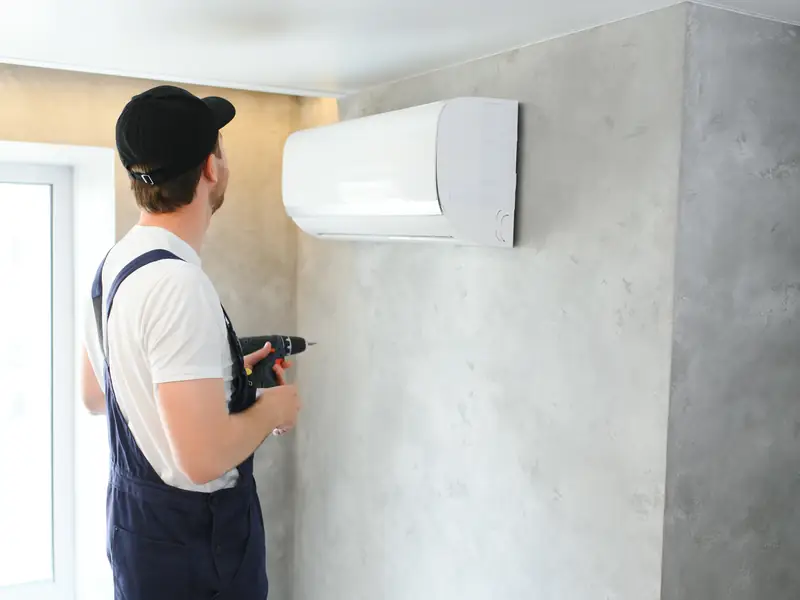 Climatisation monosplit à Agay, Anthéor et Le Trayas 2 Technicien fixant une unité murale de climatisation au-dessus d'une porte