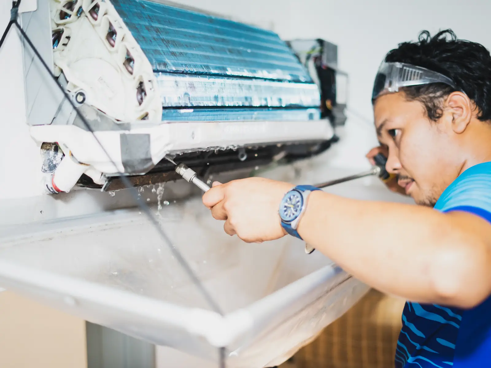 Technicien nettoyant l'échangeur d'une climatisation murale pour supprimer les mauvaises odeurs