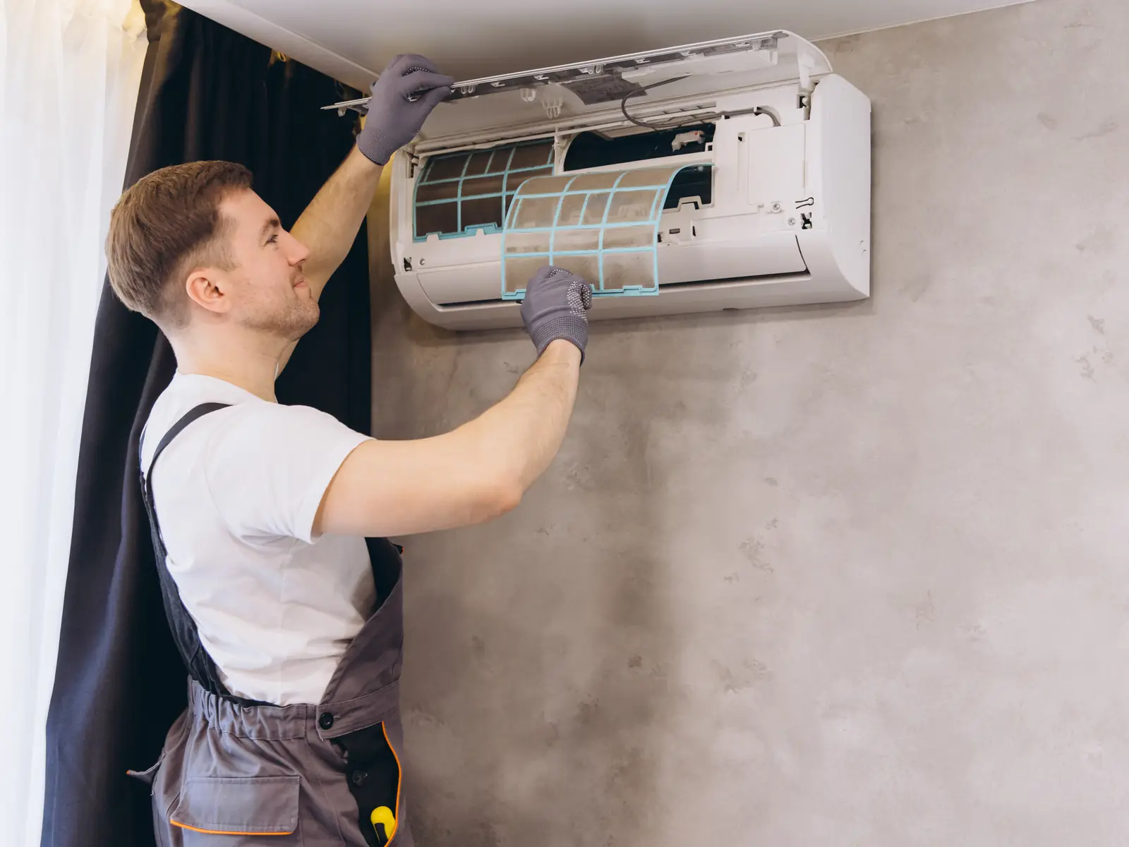 Technicien nettoyant une unité intérieure de climatisation avant sa désinfection