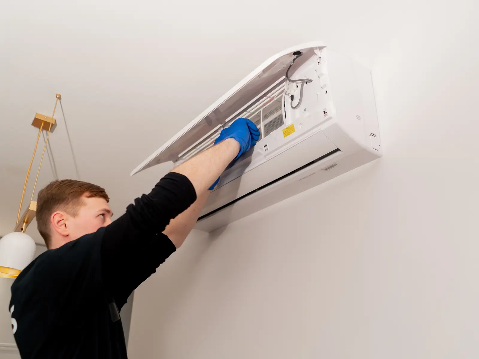 Technicien nettoyant une unité murale de climatisation avant la saison chaude