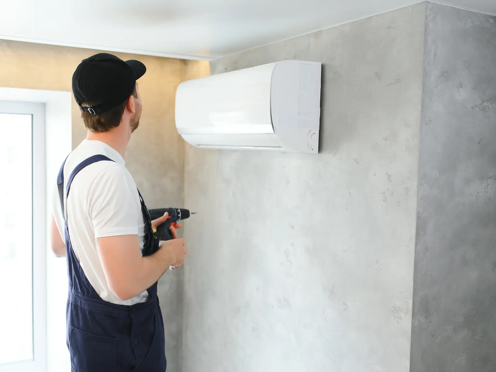 Technicien posant une unité murale de climatisation dans une pièce à vivre